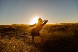 Woman posing between field at sunset