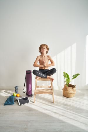 Adorable boy sitting in Lotus pose with hands in Namaste