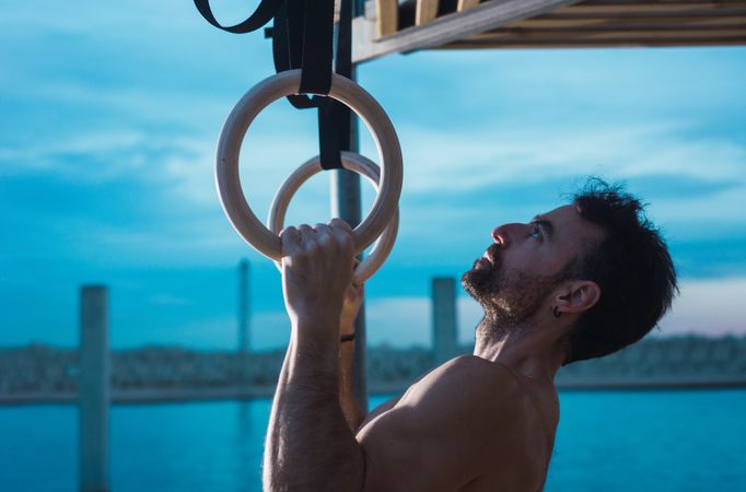 Athletic man balancing on gymnastic rings