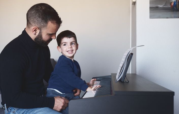 Father teaching son to play piano