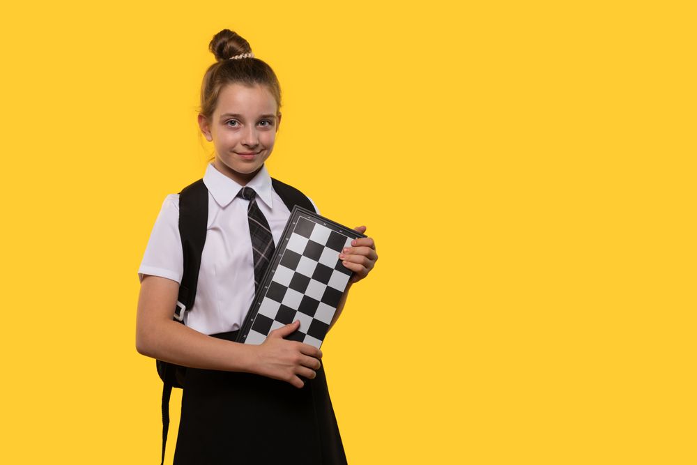 Smiling schoolgirl holds chessboard