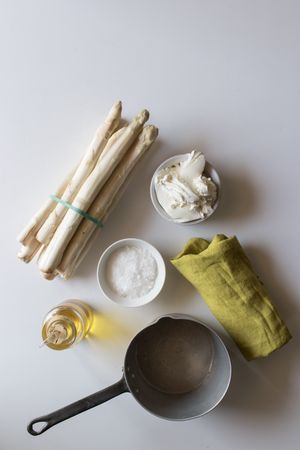 Saucepan and napkin near asparagus and condiments