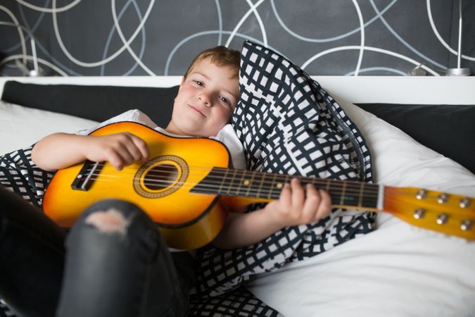 Young blonde boy playing toy guitar