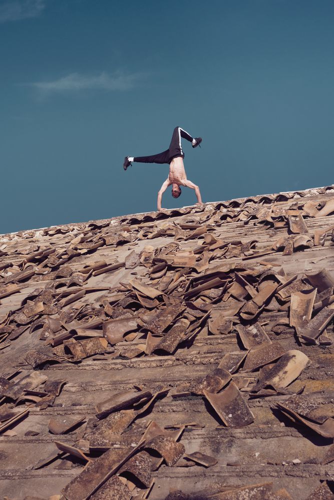 Man standing on two hands while dancing breakdance on roof