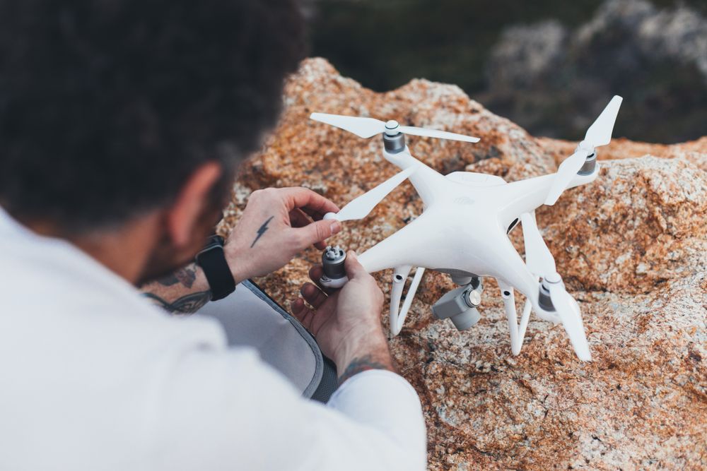 Close up of tattooed man setting up a drone outside