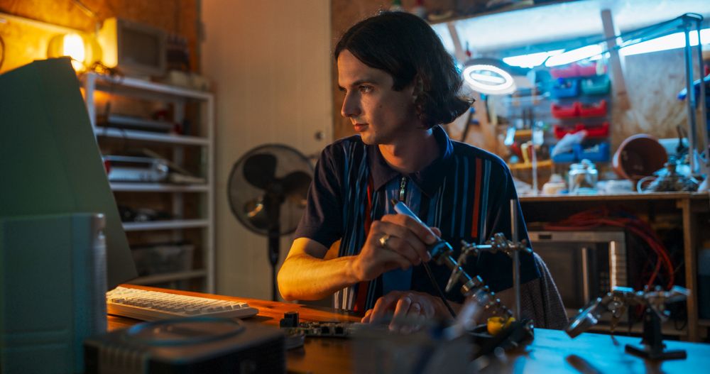 Portrait Of White Male Software Engineer Programming on Old Desktop Computer In Retro Garage In The Evening.