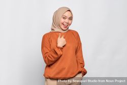 Happy woman in hijab and orange shirt in studio 4NLOe0