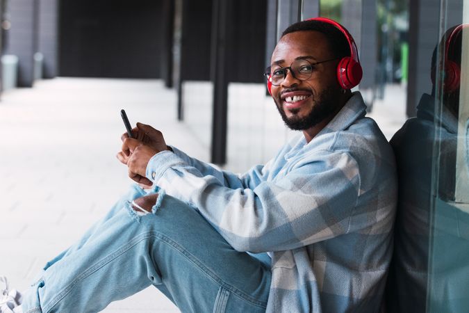 Cheerful Black man with smartphone listening to music