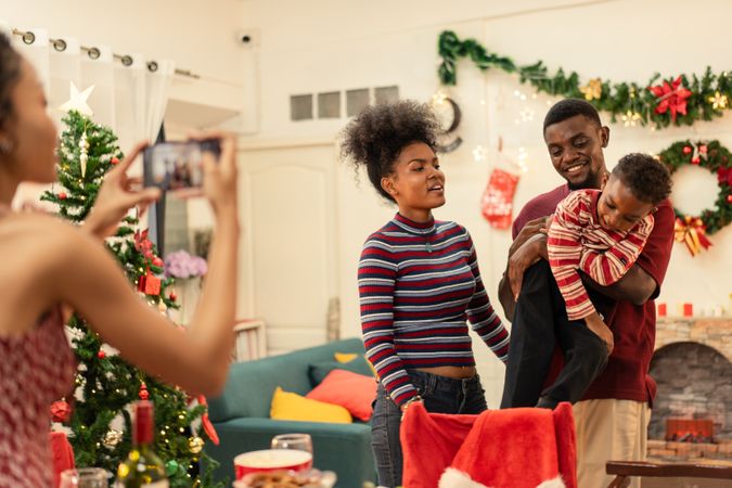 Black woman using smartphone taking picture of a family during Christmas