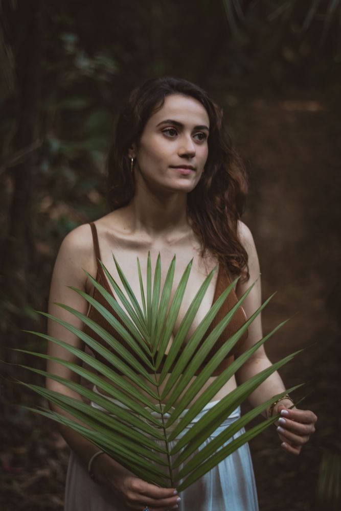 Woman standing and holding a big tree leaf