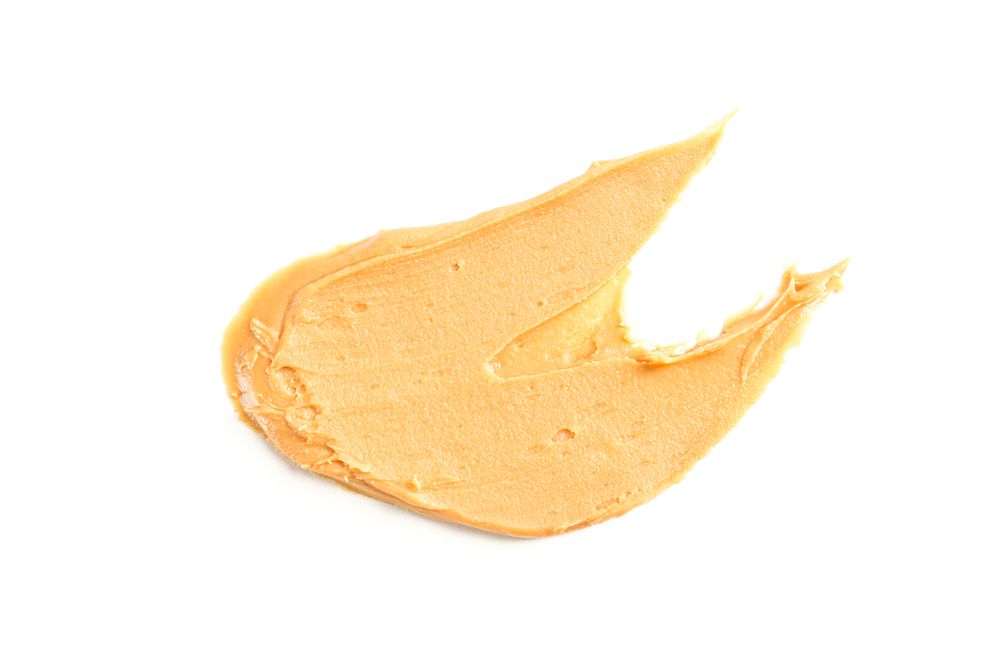 Creamy peanut butter isolated on bright background. A traditional product of American cuisine
