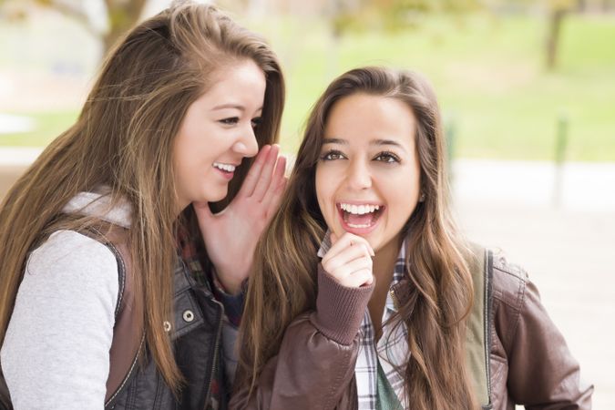 Two Female Friends Whispering Secrets Outside