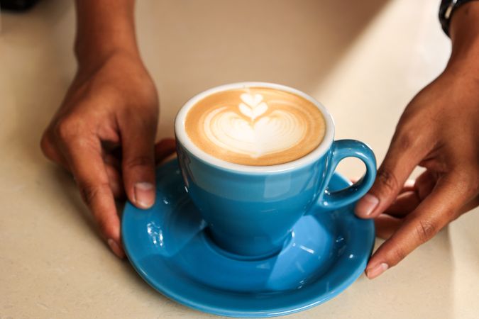 Barista Hand Holding Blue Cup with Latte Art