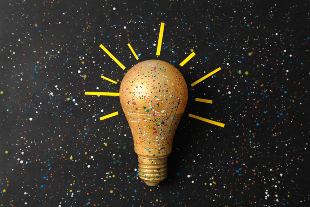 Paint splatters and spots on light bulb and dark background. Creative idea concept