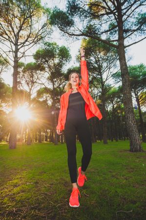 Excited sportswoman with arms raised in park