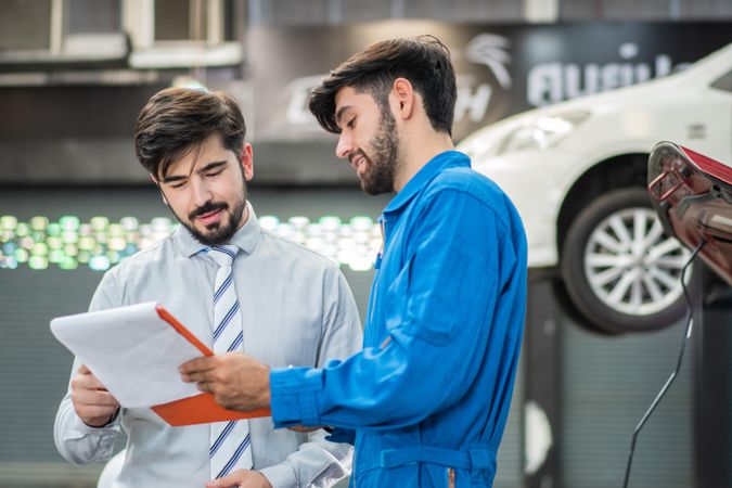 Technician explaining repairs to customer on clipboard