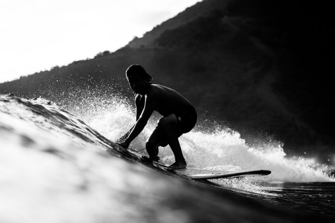 Grayscale photo of man surfing sea wave