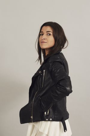 Serious pensive young female wearing leather jacket in studio
