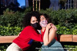 Two female friends in park together with protective medical masks 5R9GW0