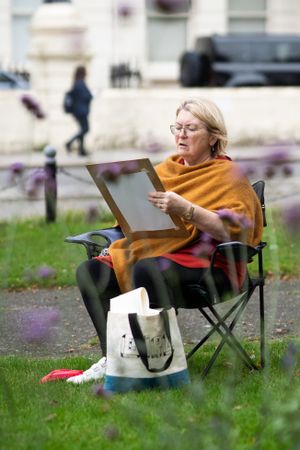 Serious older woman drawing in park outside
