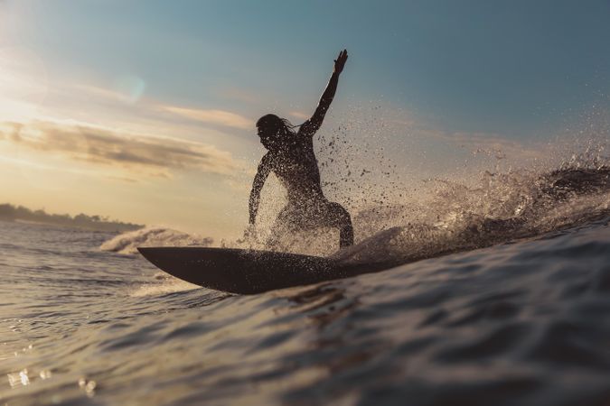 Man on surf board on waving water at sunset