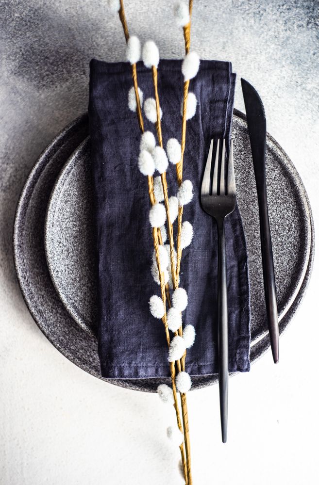 Table setting for Easter dinner with pussy willow on navy napkin