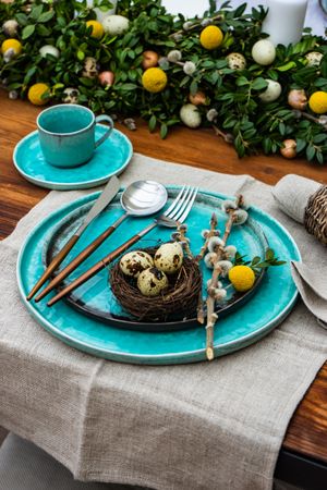 Festive table setting for Easter holiday dinner with speckled eggs in nest