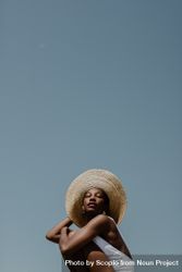 Woman in a light swimsuit wearing a large sun hat 43rKg5