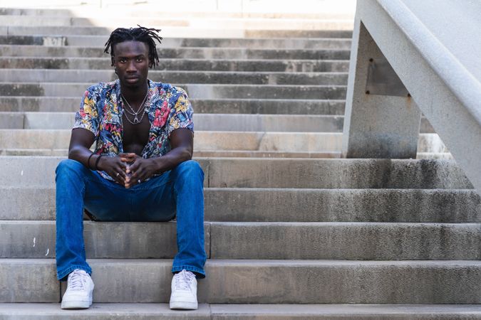 Stylish Black hipster man sitting on stairs in city