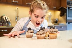 Excited kid contemplating cupcakes on kitchen table