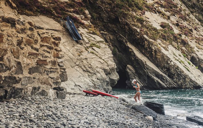 Woman with paddle board near cliff and sea