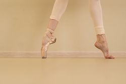 Ballet dancer on pointe with one foot, barefoot with other