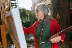 Mature woman painting on canvas in garden