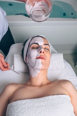 Woman resting with eyes closed while having a face mask applied
