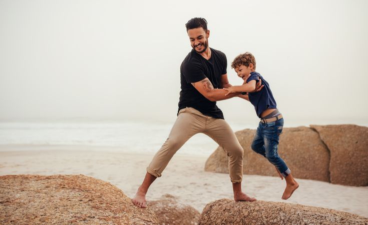Young man and little boy having fun at the rocky beach
