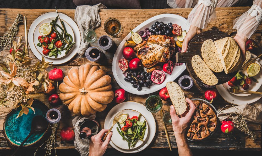 Autumnal table with squash and candles with woman serving bread to man