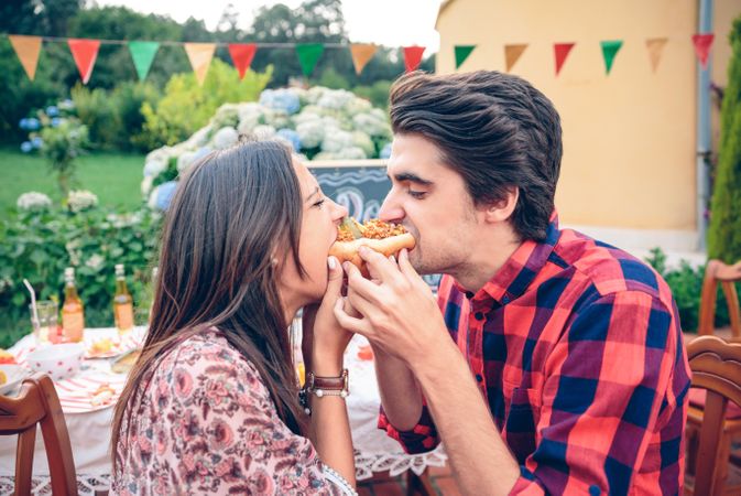 Funny young couple eating an American hot dog together