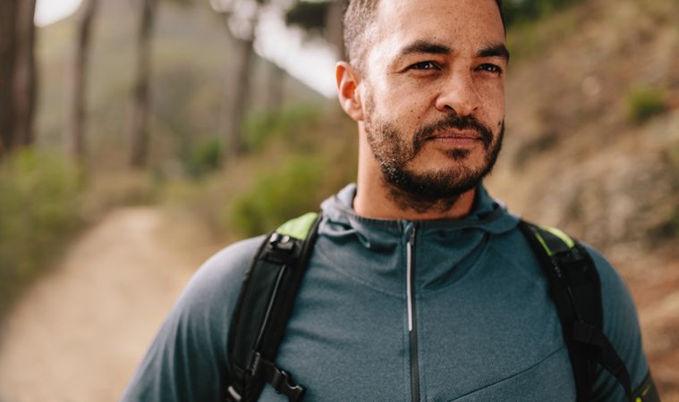 Portrait of fit man standing outdoors on mountain trail