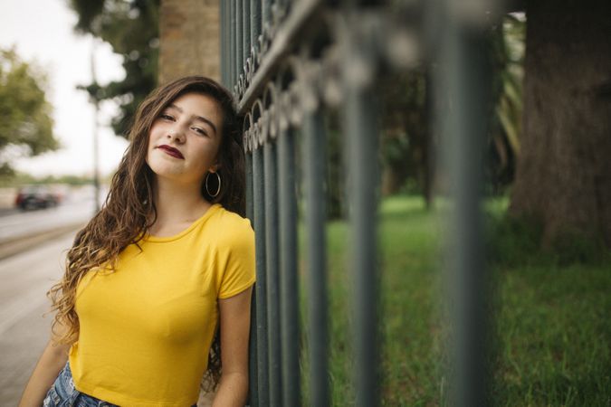 Glad woman leaning on park fence