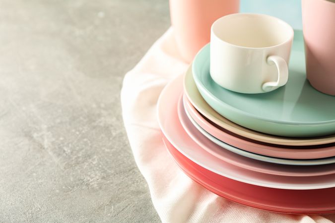Color plates and cups stacked on grey table, space for text
