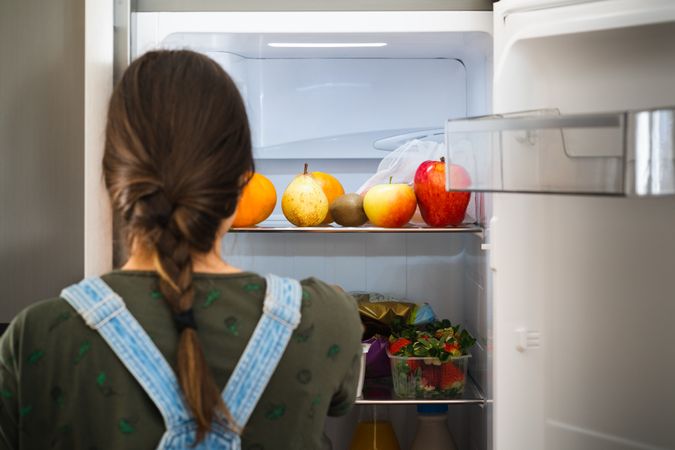 Crop woman taking fruit from fridge