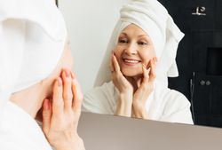 Cheerful woman admires her reflection in the bathroom mirror