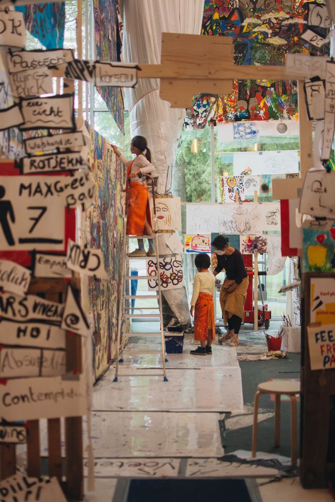 Girl drawing on canvas while teacher guiding another girl with drawing in a gallery