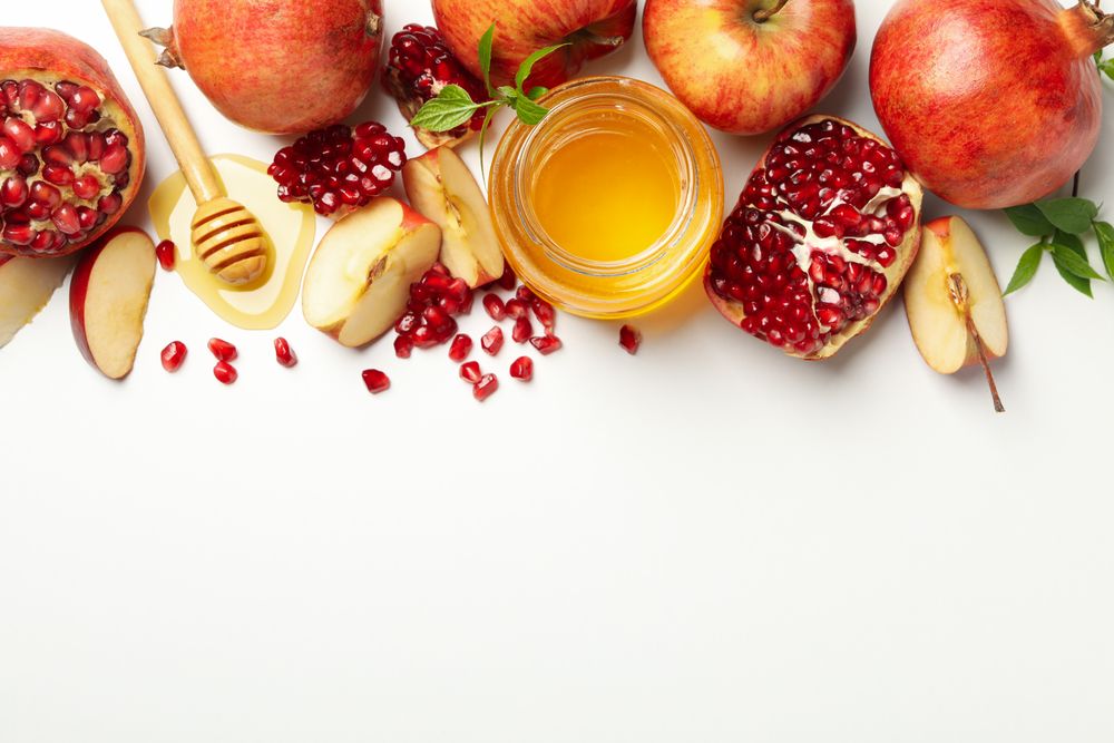 Glass honey pot with pomegranate, and an apple quarters with copy space
