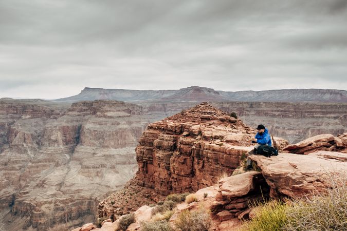 Male relaxing on cliff and admiring picturesque view