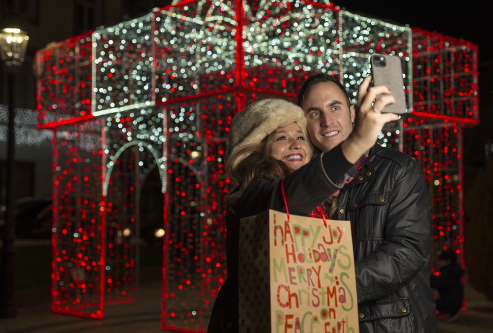 Happy couple standing and taking selfie on smartphone in night