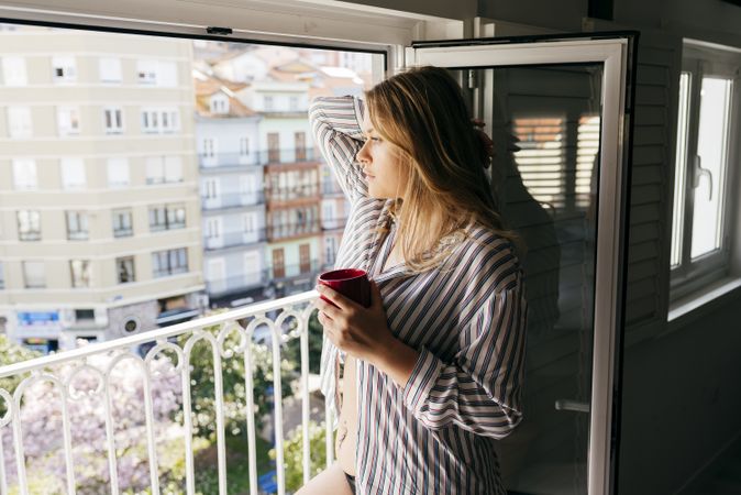 Young thoughtful woman with cup looking at street