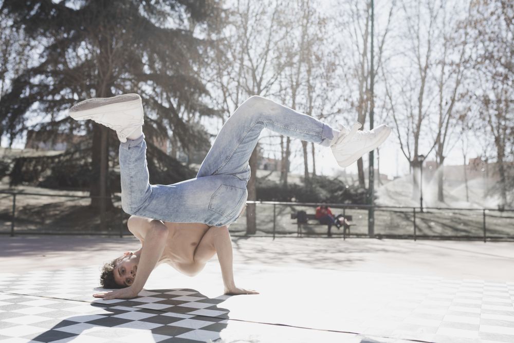 Shirtless man dancing break dance in park