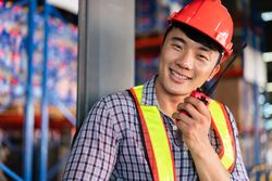 Smiling man in PPE gear talking on walkie talkie