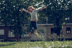 Cheerful boy jumping in meadow in countryside